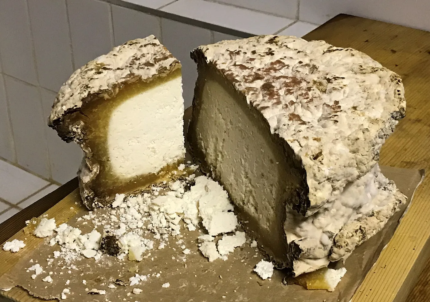 Un pain de Graukäse tyrolien entamé : croûte marbrée de gris, pâte blanche et friable.