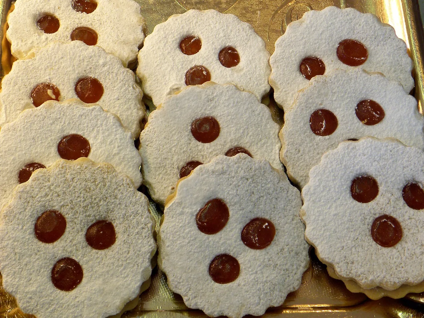Linzer Augen à trois « yeux », poudrés de sucre glace, en vitrine de boulangerie.