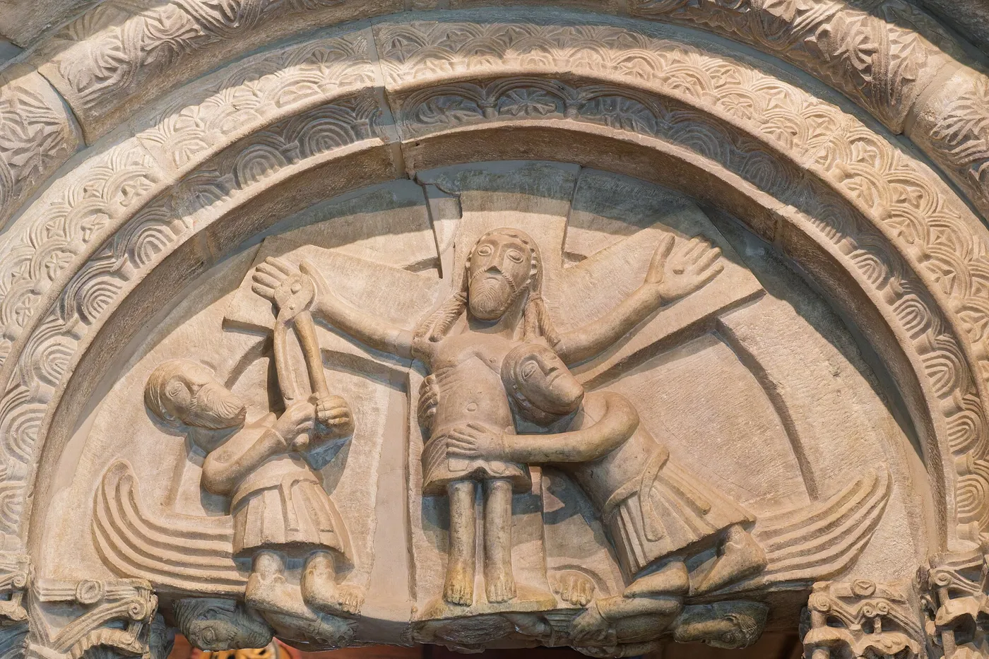 Tympan roman du portail de la chapelle de Schloss Tirol : Joseph d'Arimathie et Nicodème descendent le Christ de la croix.